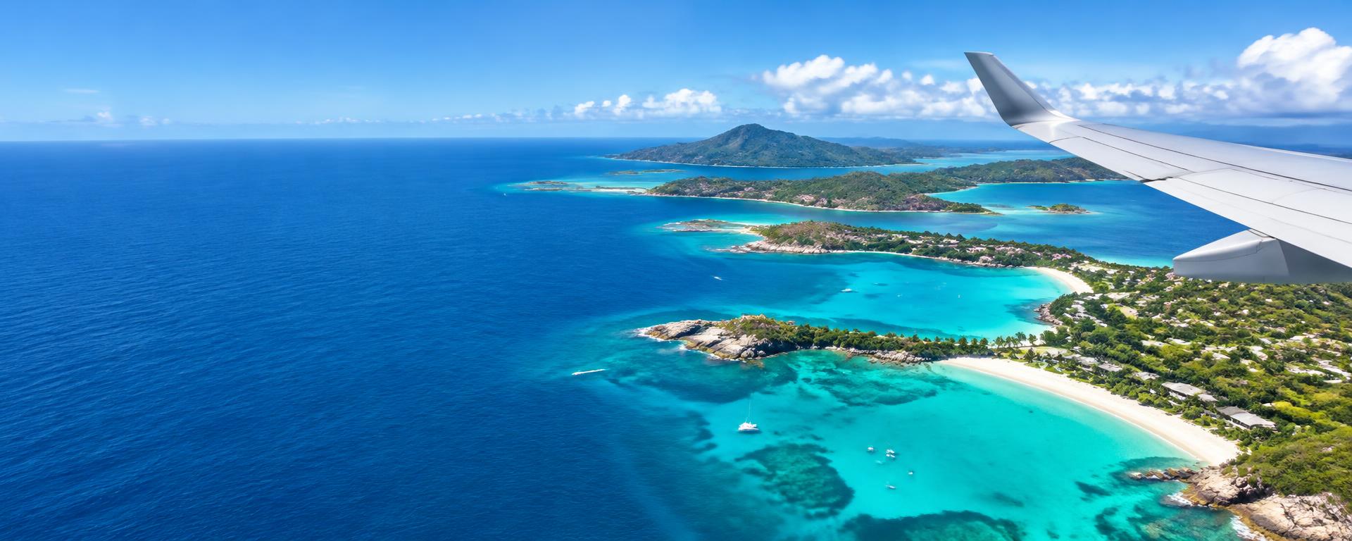 Airplane wing above turquoise island beaches